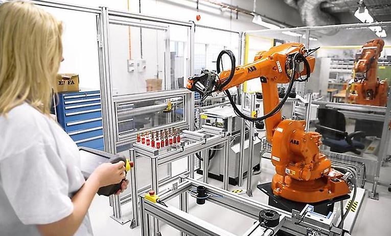 Elev framför robot i industrimiljö